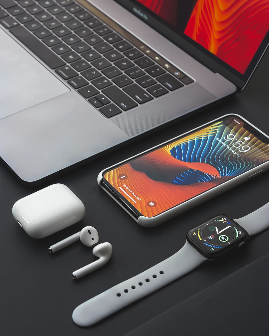 Notebook, teléfono, audífonos y reloj sobre fondo oscuro